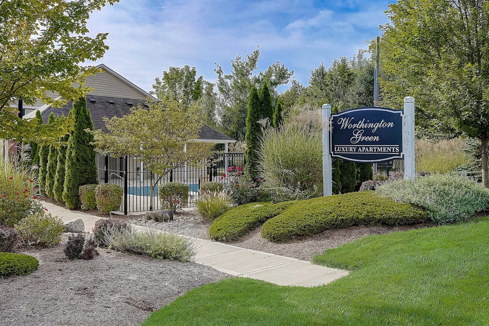 the entrance to a residential community with landscaping and trees at The Worthington Green